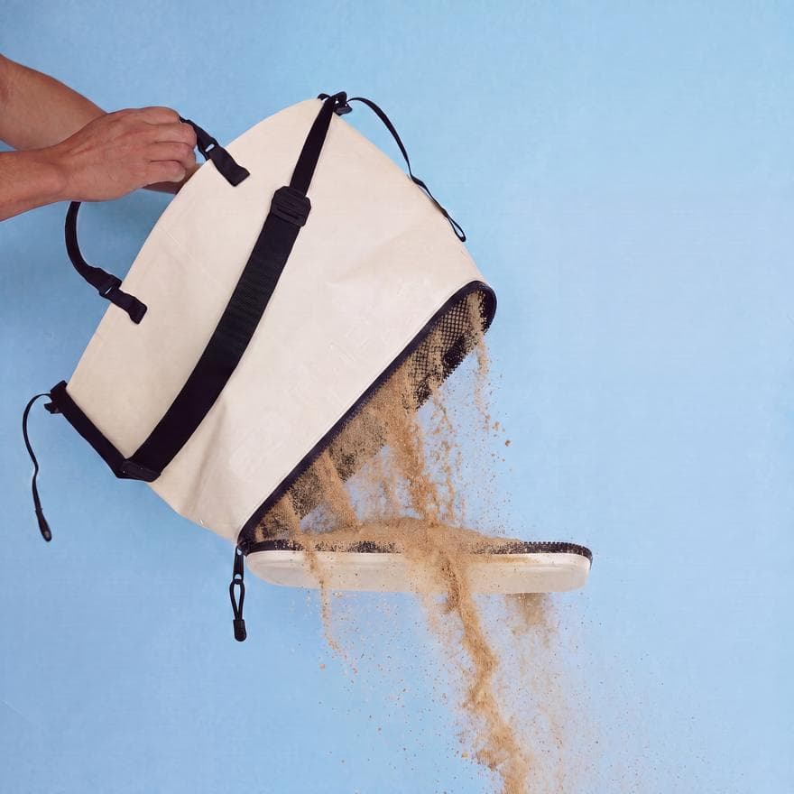 Sunday Proof bag held at an angle with its base unzipped, sand pouring out through a mesh bottom